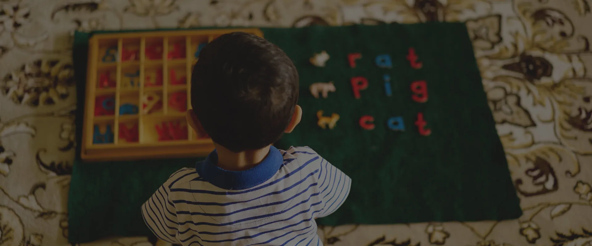 A Preschool child working with a Montessori moveable alphabet
