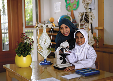 Elementary student with teacher at the microscope