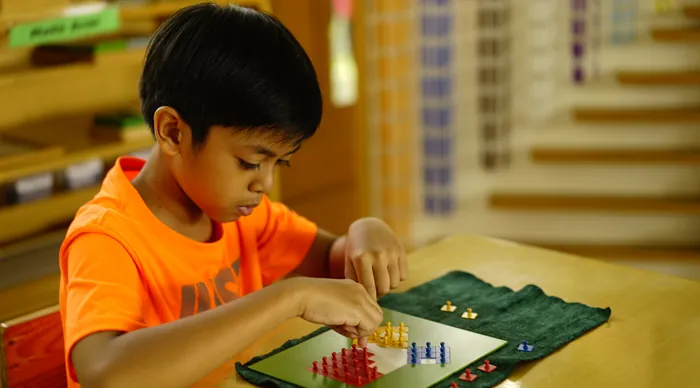 A child placing coloured pegs on a Montessori math board