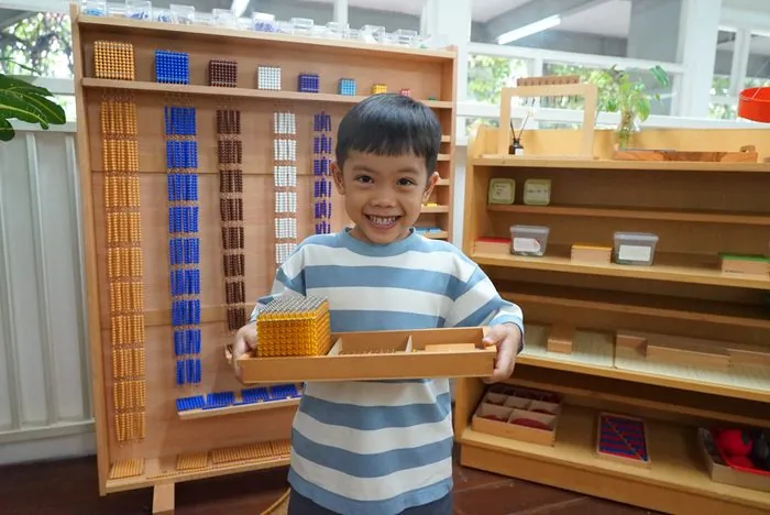 A child carrying the golden bead material he fetched from the shelf
